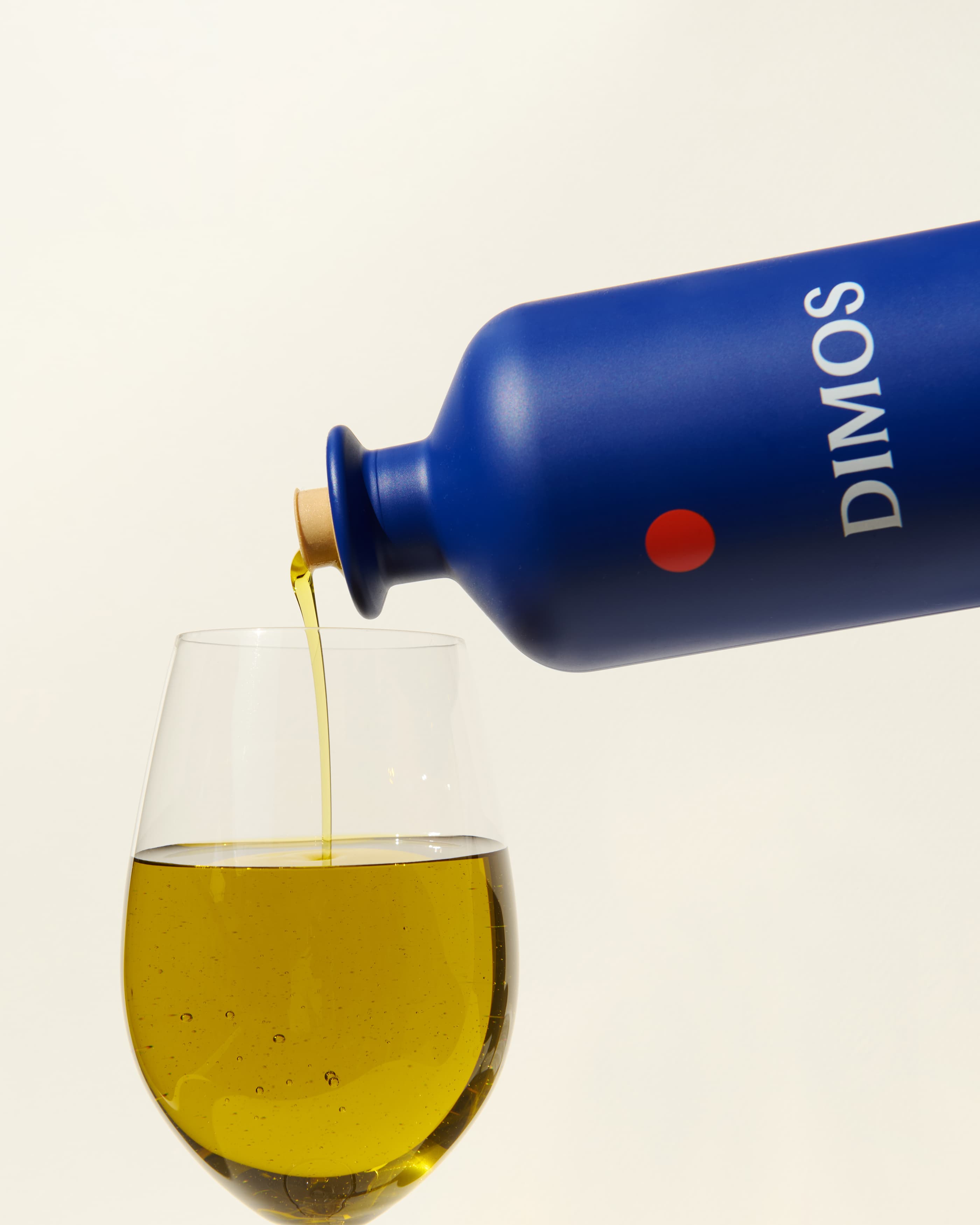 DIMOS extra virgin olive oil being poured into a glass